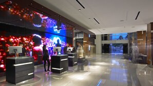 Un vestíbulo moderno con una pared de pantalla digital, mostradores de recepción y un espacio amplio y bien iluminado.
