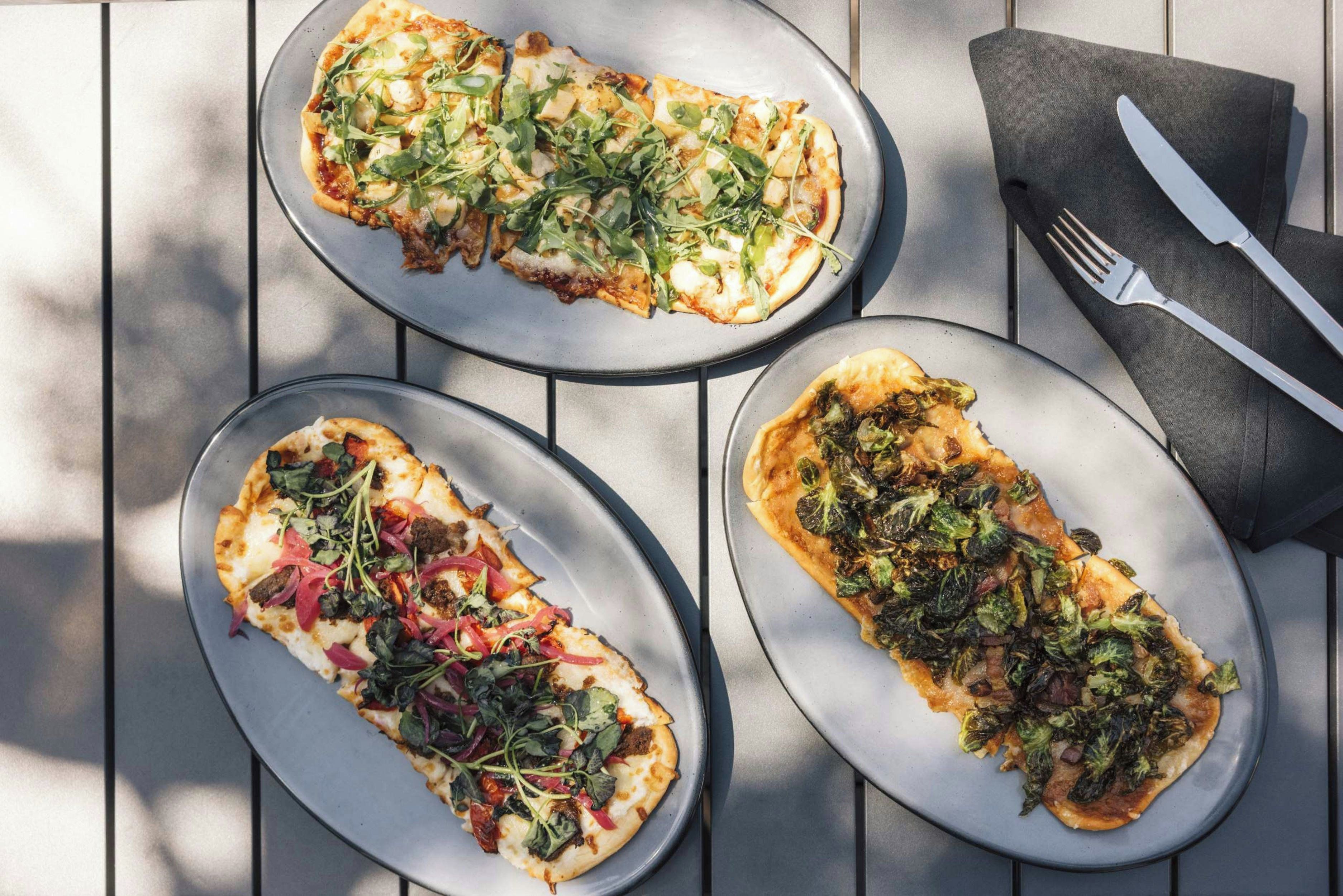 Three oval plates with food on a table.