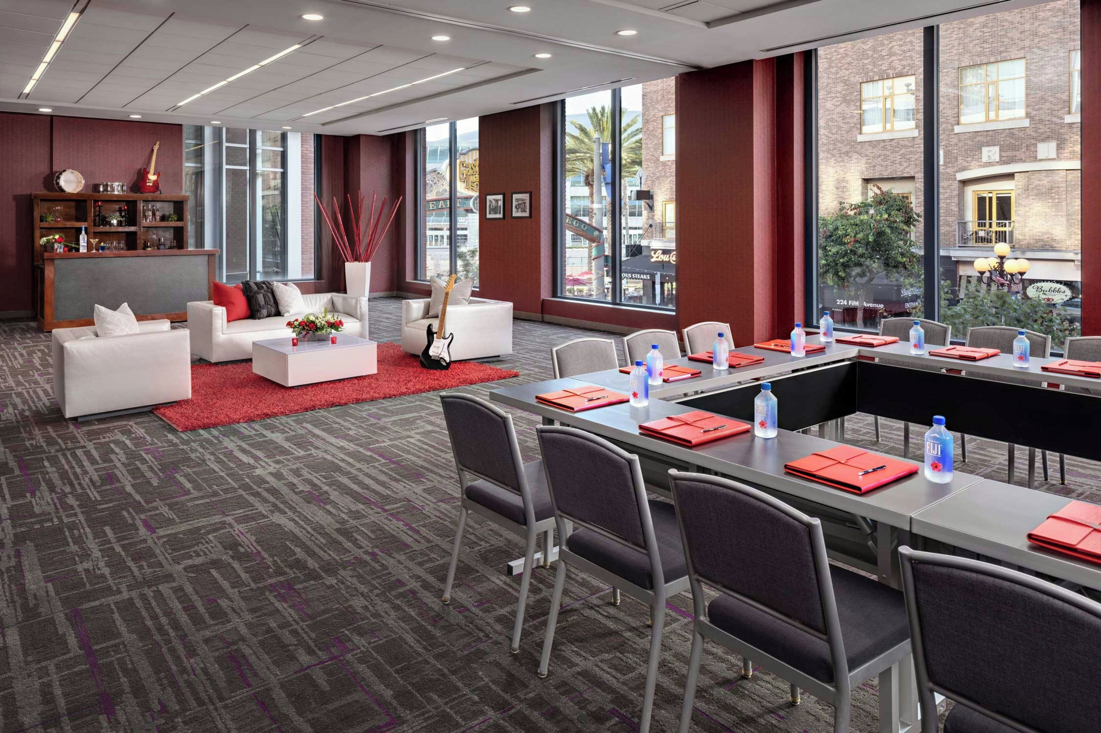 A modern hotel room with a large dining table, comfortable seating, and a bar area.