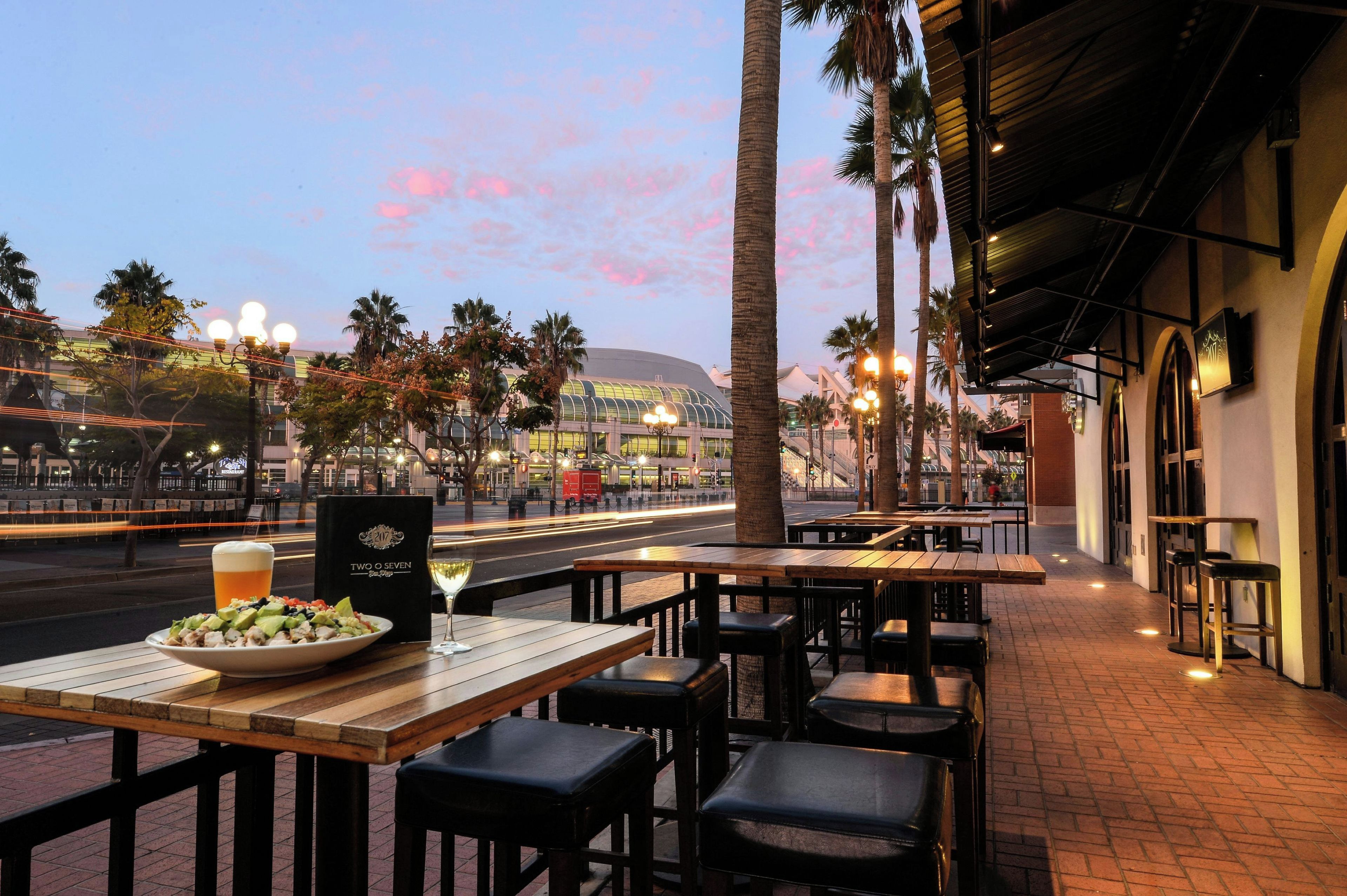 An outdoor dining area with tables and chairs, a bowl of food, and a drink on a table.