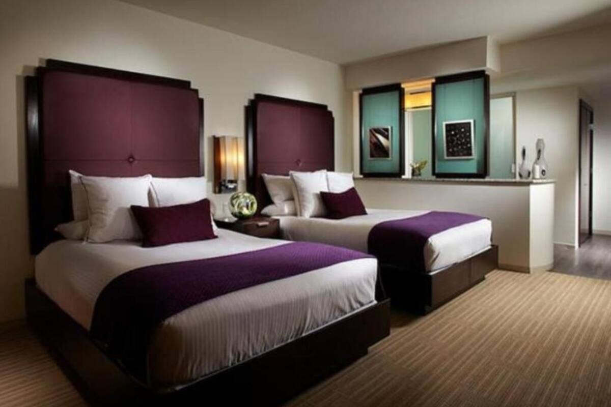 Une chambre d’hôtel avec deux lits, un bureau et un miroir.