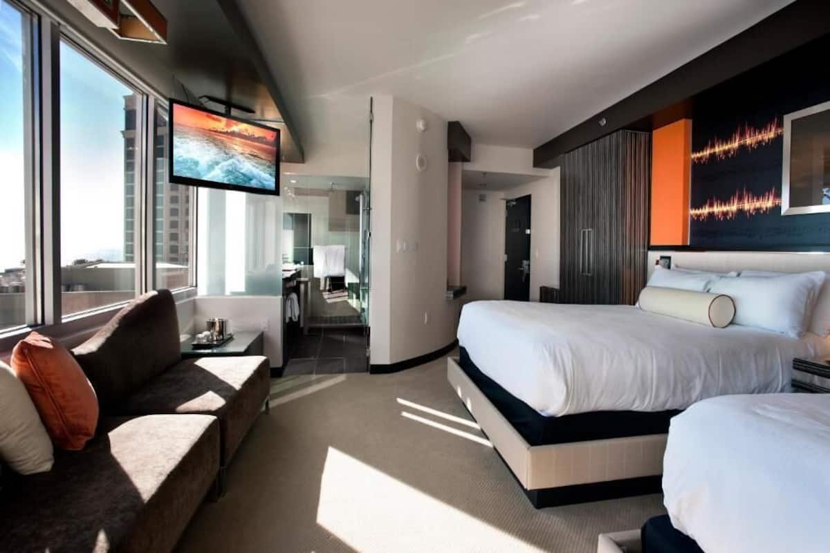 Une chambre d’hôtel moderne dotée d’un grand lit, d’un canapé, d’une télévision et offrant une vue sur la ville.