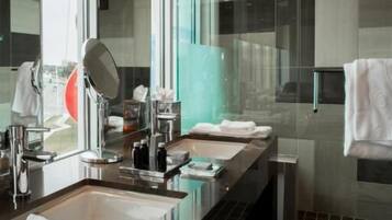 Un baño moderno con cabina de ducha de vidrio, un espejo grande y un lavamanos doble.