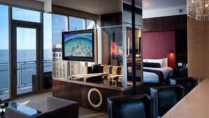 Quarto de hotel moderno com uma televisão grande, mesa de bilhar, sofá e cama.