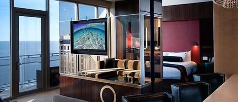 Una habitación de hotel moderna con una televisión grande, una mesa de billar, un sofá y una cama.