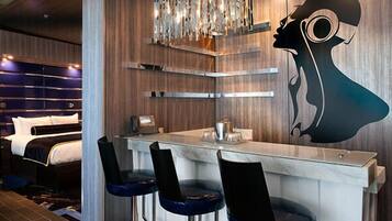 Una habitación de hotel moderna con una zona de bar, una cama y una original pieza de arte en la pared.