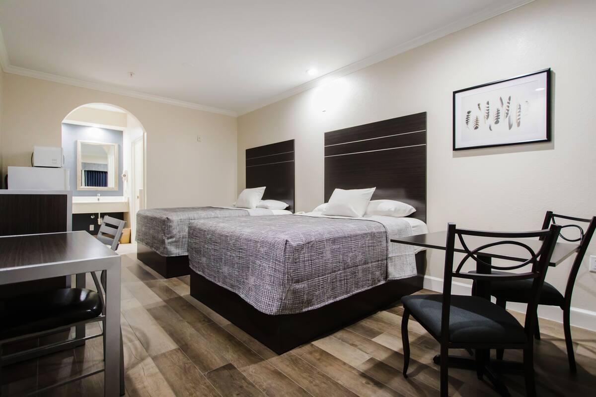 Ein Hotelzimmer mit zwei Betten, einem Esstisch und einem Stuhl.