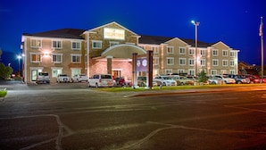 Un hotel de varios pisos con un cartel llamativo que dice 'Yellowstone', un estacionamiento con varios coches y un asta de bandera con la bandera estadounidense.