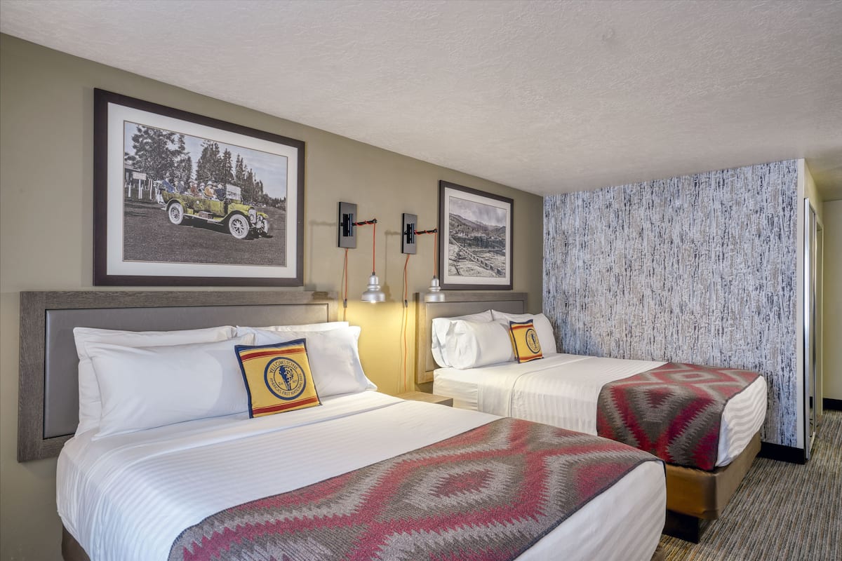 Une chambre d’hôtel avec deux lits, une photographie encadrée au mur et un rideau à motifs.