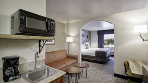 Habitación de hotel con kitchenette, un sofá, una mesa pequeña, una cama y vistas a la ciudad.