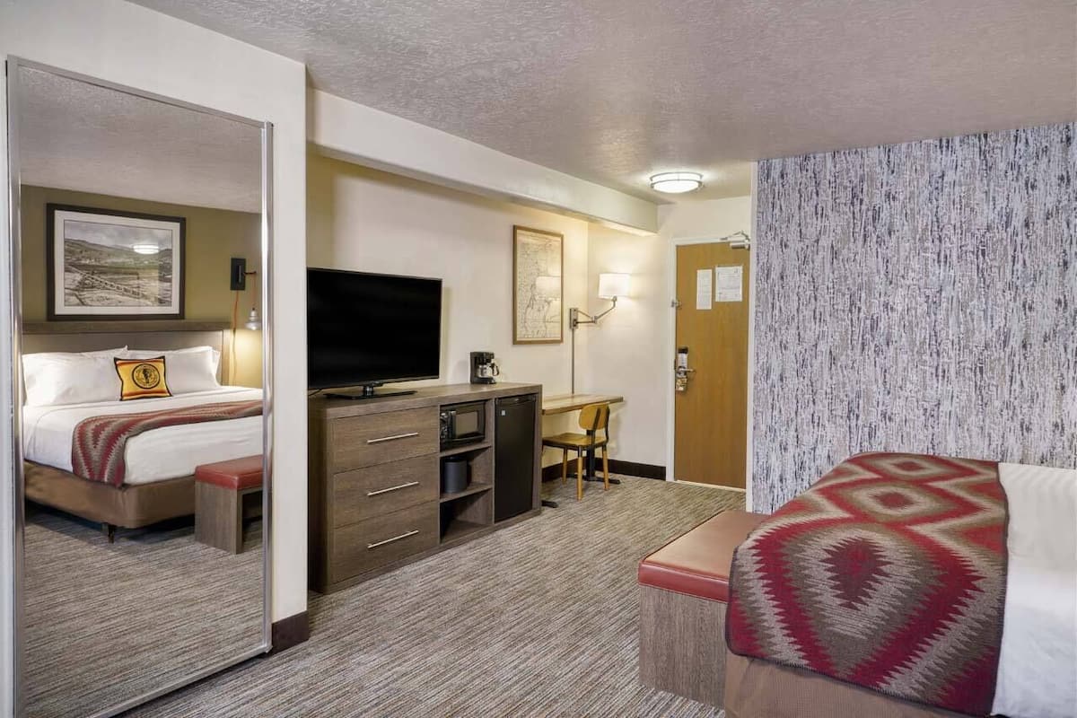 Une chambre d’hôtel équipée d’un lit, d’un bureau, d’une télévision, d’un four à micro-ondes et d’un petit coin salon.