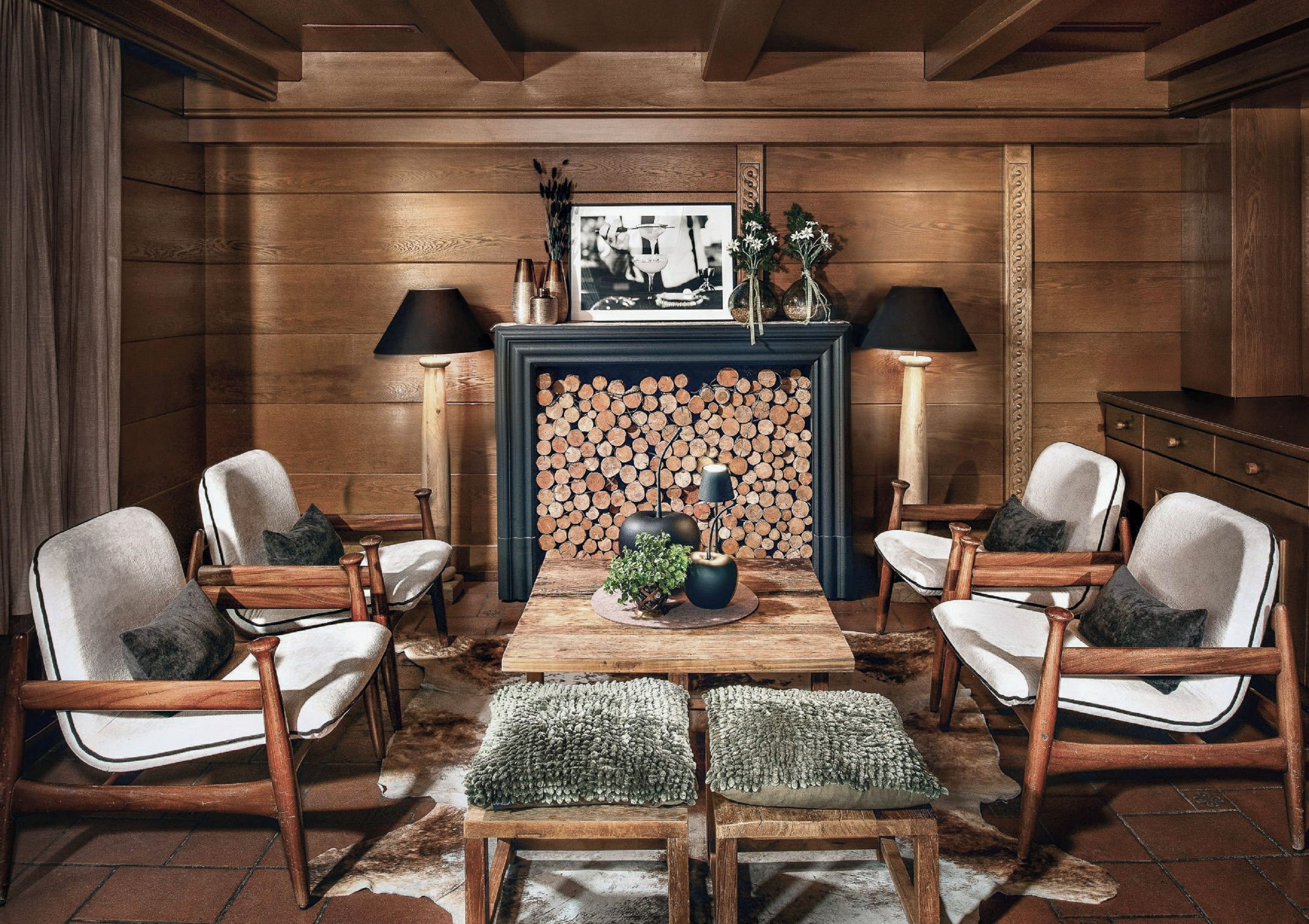 A room with a fireplace, wooden walls, and a table with chairs.