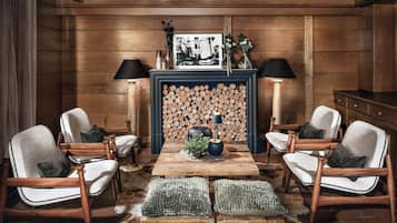 A room with a fireplace, wooden walls, and a table with chairs.