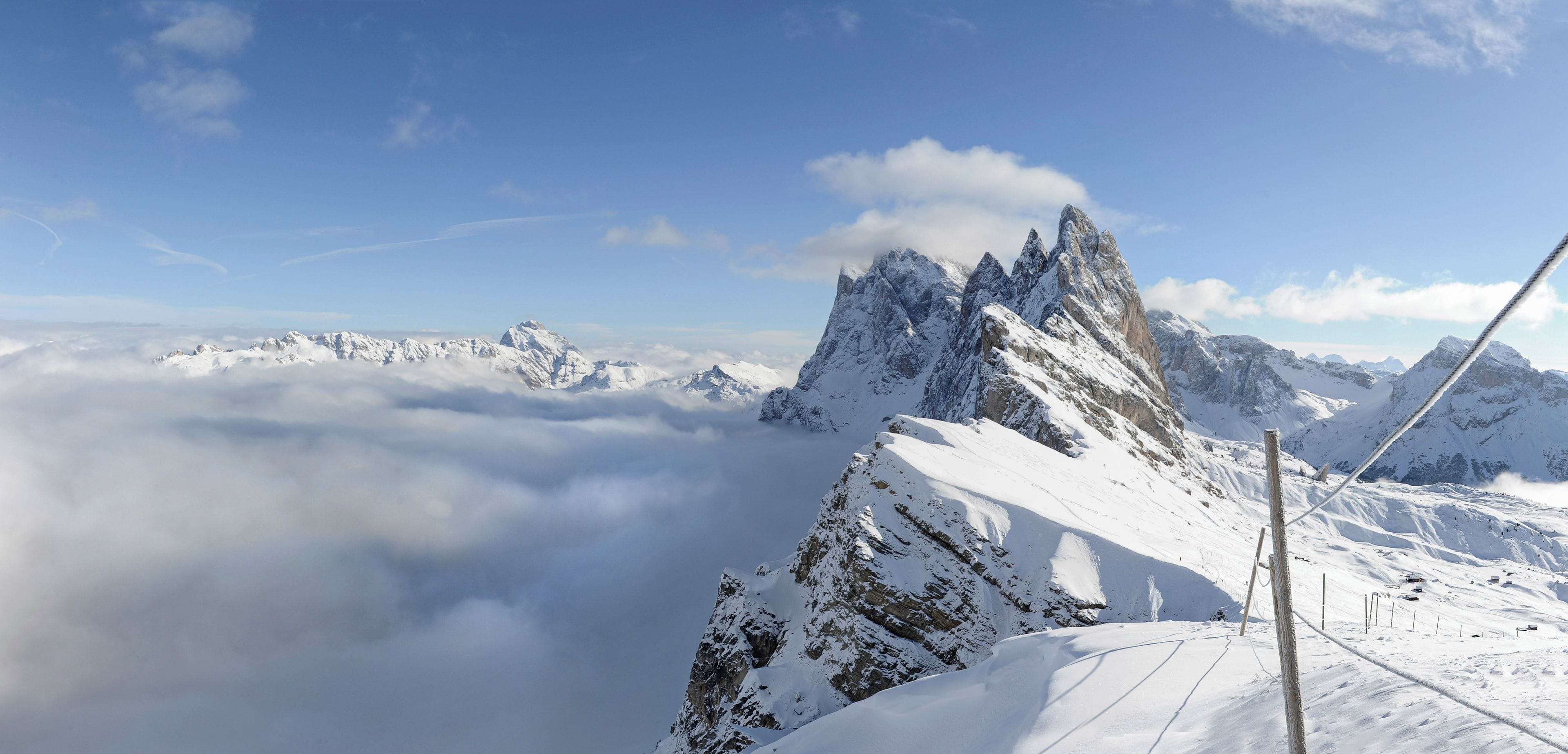 A snow-covered mountain peak with a clear sky and a view of the valley below.