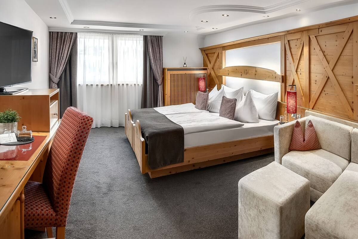 Een hotelkamer met een bed, een bureau, een televisie en een groot raam met gordijnen.