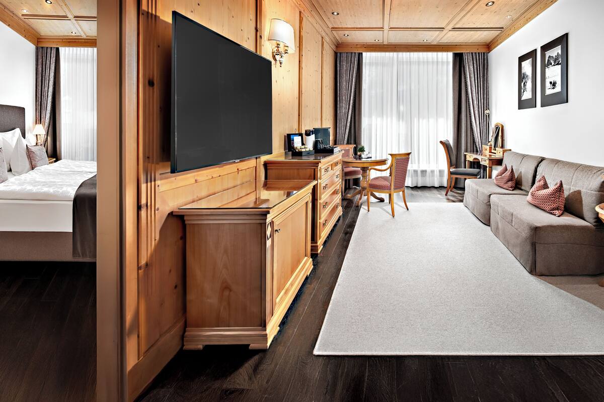 Een hotelkamer met een bed, een televisie, een bureau, een bank en een zithoek.