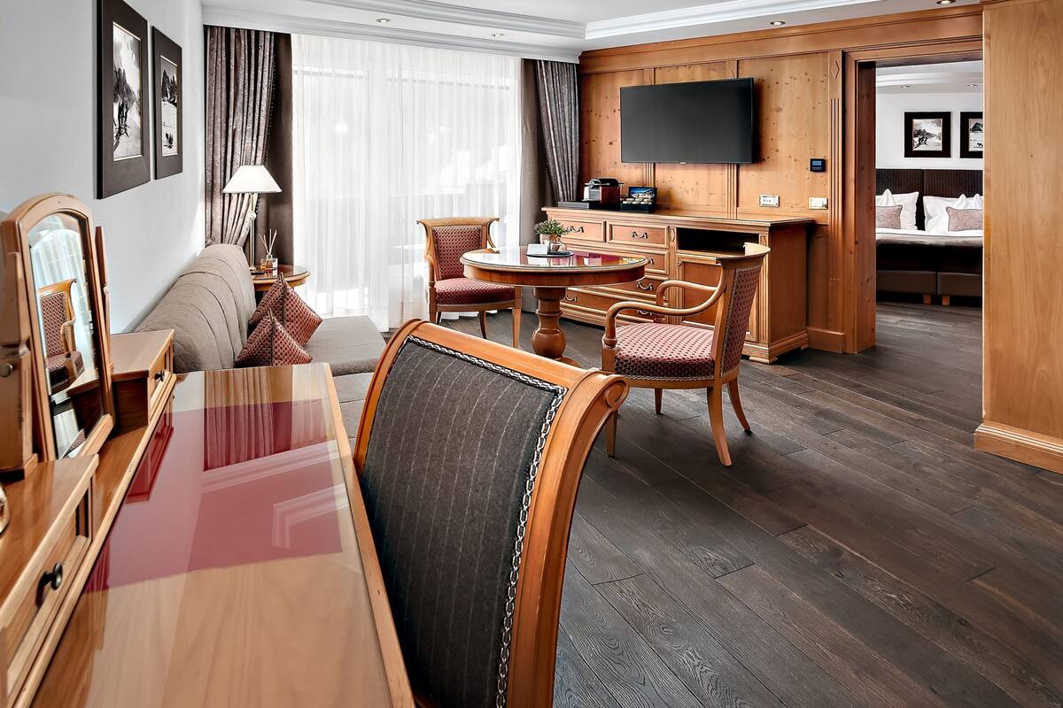 Een hotelkamer met een eethoek, een aan de muur bevestigde televisie en een bed met hoofdeinde.