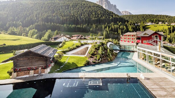 Een resort met een zwembad, een houten terras en uitzicht op een berg.