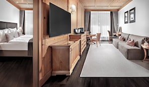 Een hotelkamer met een bed, een televisie, een bureau, een bank en een eethoek.