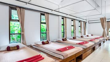 Comfortable beds are arranged in a modern room with large windows and a geometric ceiling.