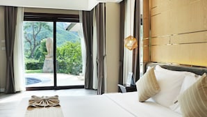 A hotel room with a large bed, a view of greenery and a hot tub outside, and a wooden headboard. - Mida Resort Kanchanaburi (Kanchanaburi)