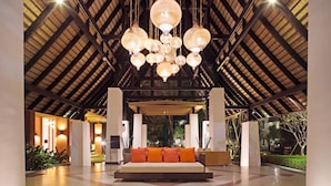 A spacious lobby with a high ceiling, a central seating area with orange cushions, and a large chandelier. - Mida Resort Kanchanaburi (Kanchanaburi)
