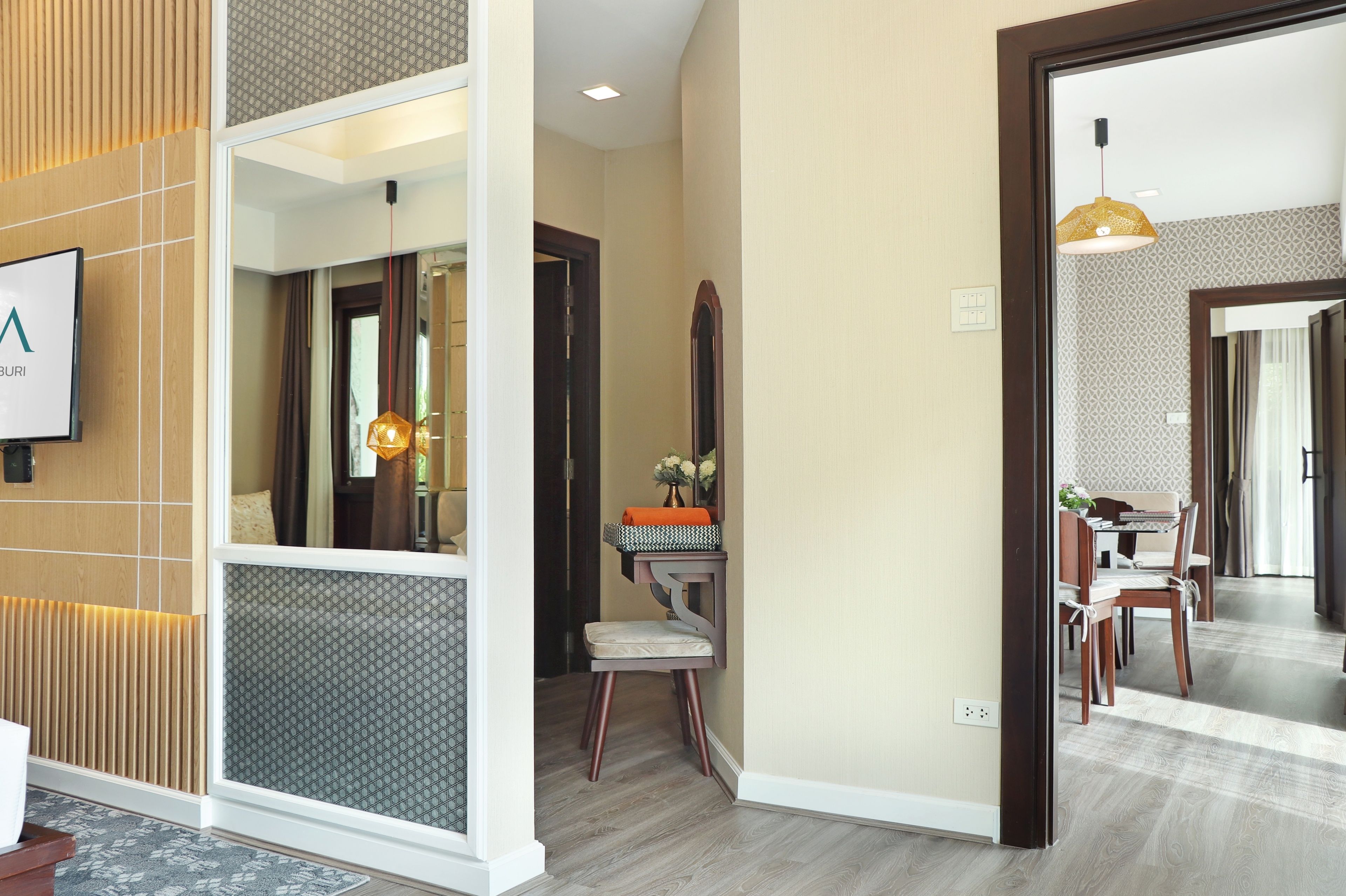 A hotel reception area with a modern design, featuring a reception desk, a seating area, and a dining space visible through an open door.