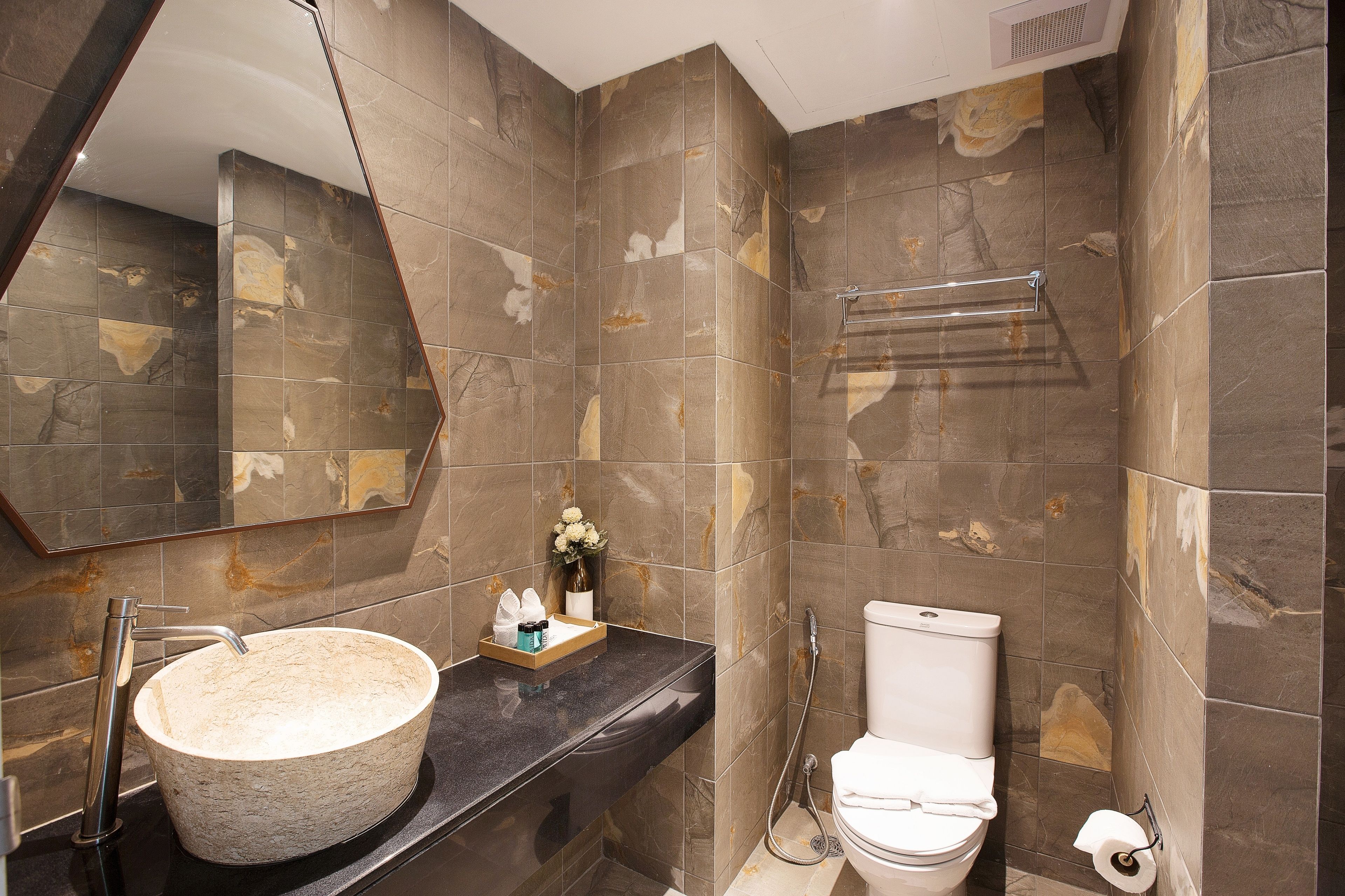 A bathroom with a large round sink, a toilet, and a towel rack.