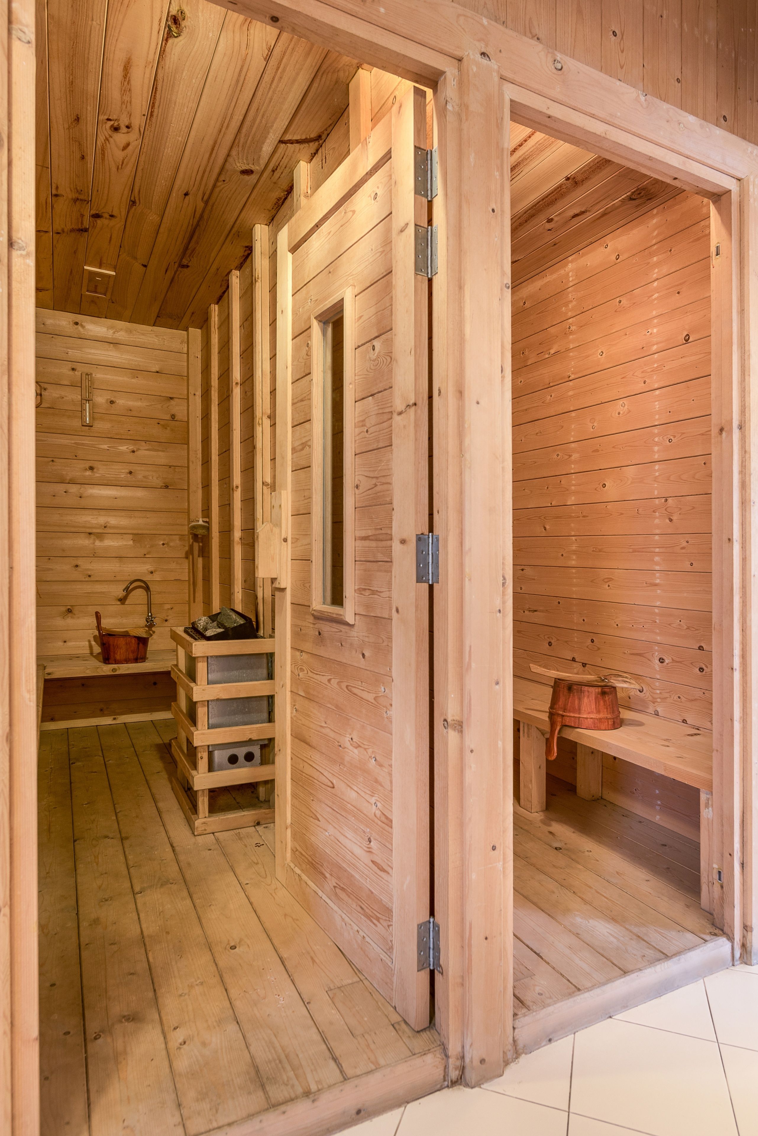 Un sauna en bois avec un banc, un lavabo et un petit meuble en bois.