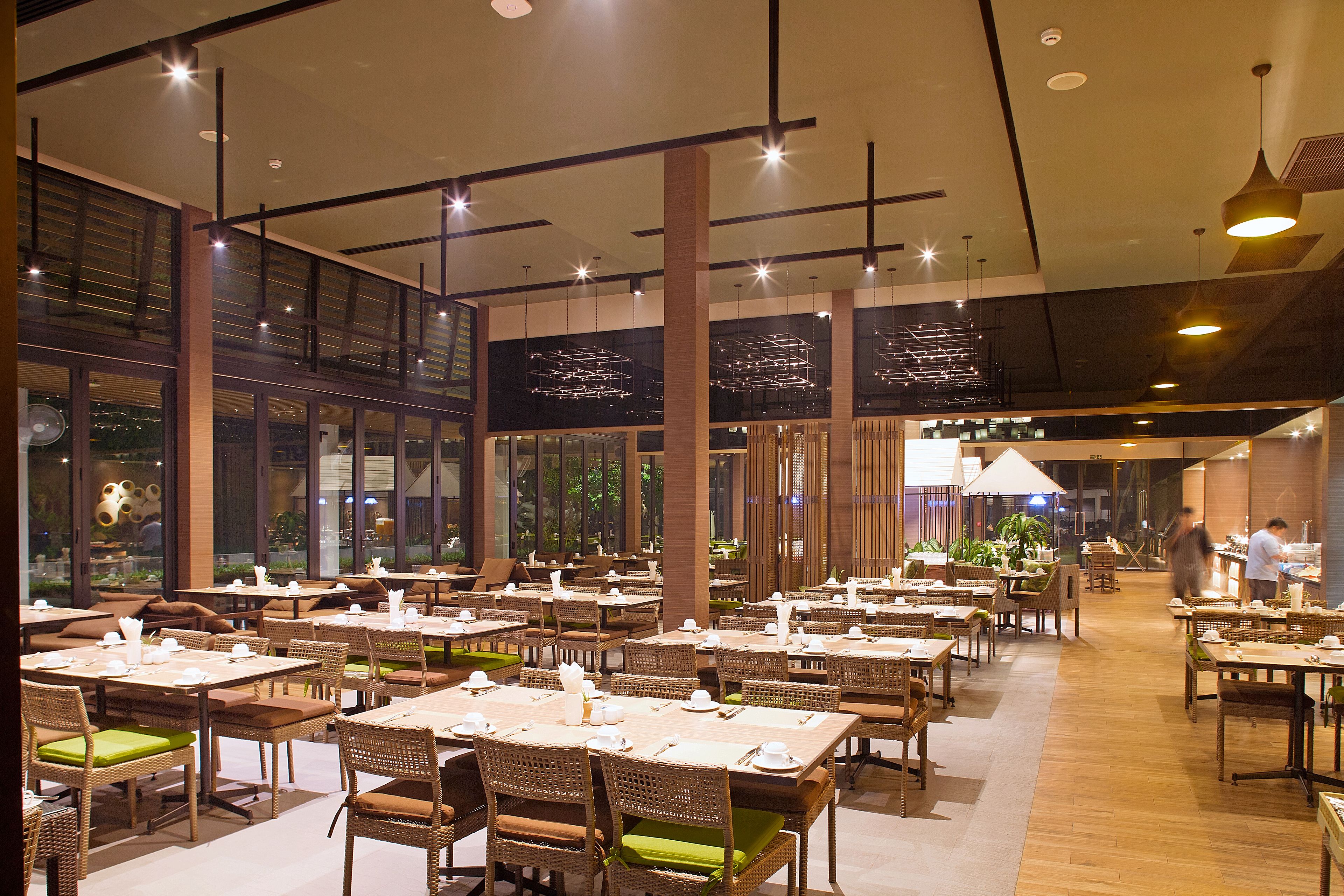 Un restaurant spacieux doté de nombreuses tables et chaises, de grandes fenêtres et d’un aménagement intérieur moderne.