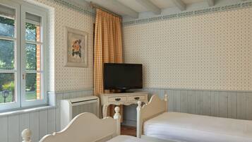 A bedroom with two beds, a television, and a window with curtains.