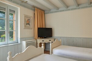 Un dormitorio con dos camas, televisión y ventana con cortinas.
