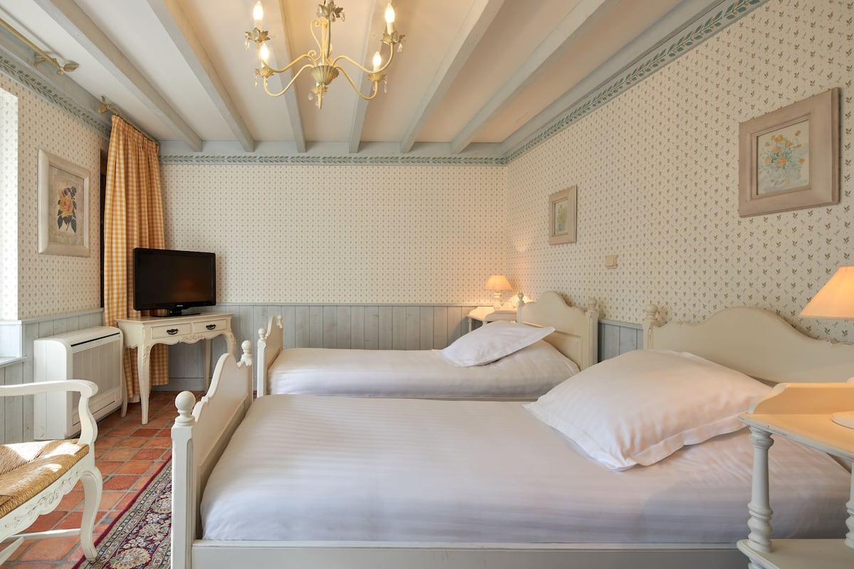Un dormitorio con dos camas, televisión, escritorio y candelabro.