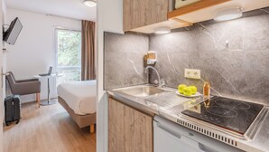 A compact kitchenette with a built-in microwave, a sink, and a stovetop. - Sejours & Affaires Nantes La Beaujoire (Nantes)