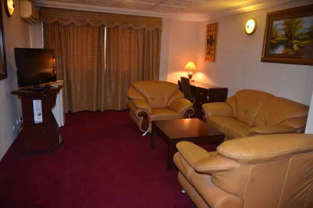 A living room with a red carpet, two sofas, a coffee table, a TV, and curtains.