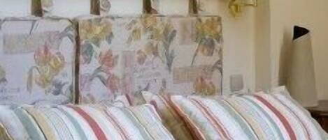 A bedroom with a bed, pillows, a nightstand, a lamp, and a framed picture on the wall.