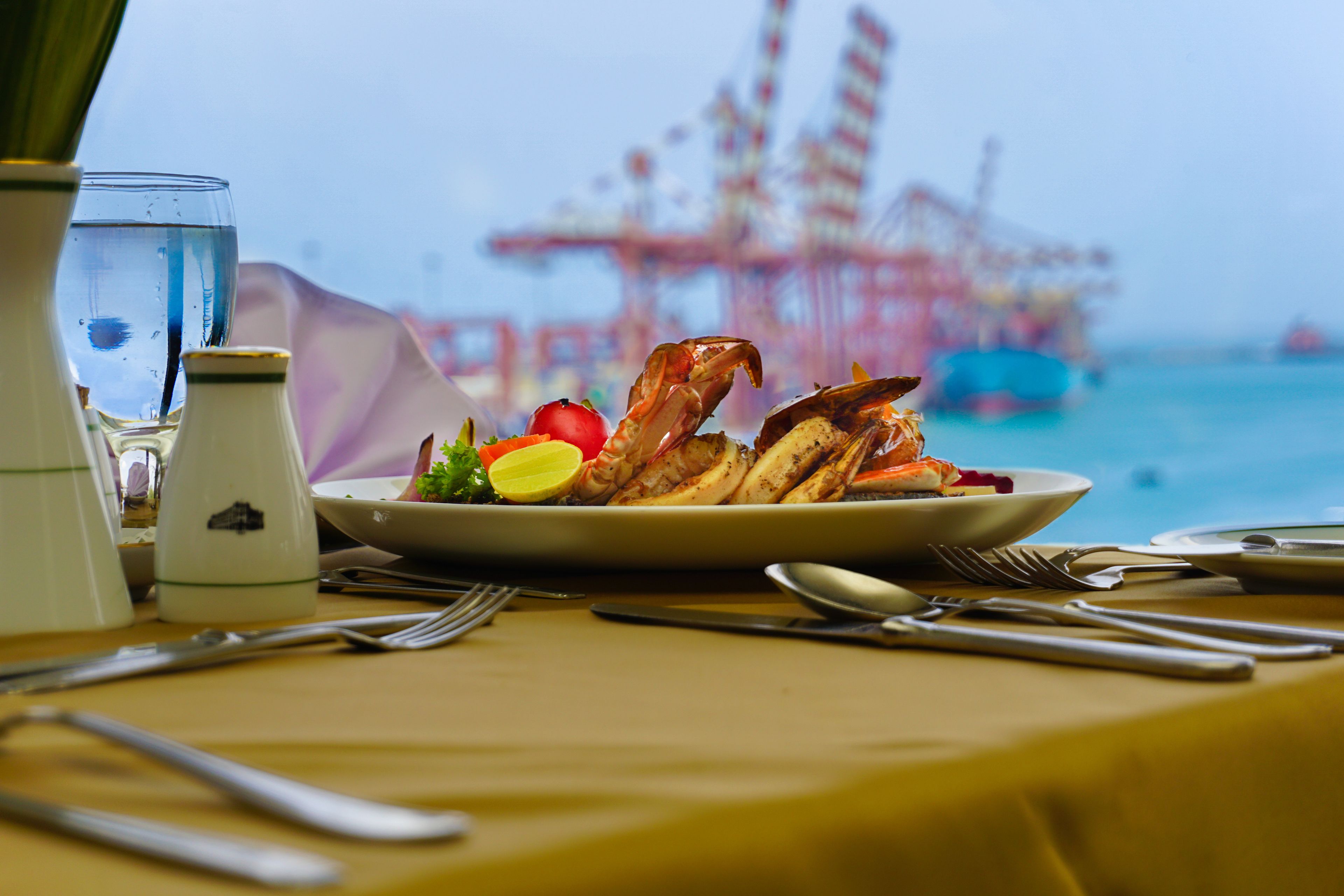 Una mesa de comedor con un plato de comida, cubiertos y un vaso de agua.