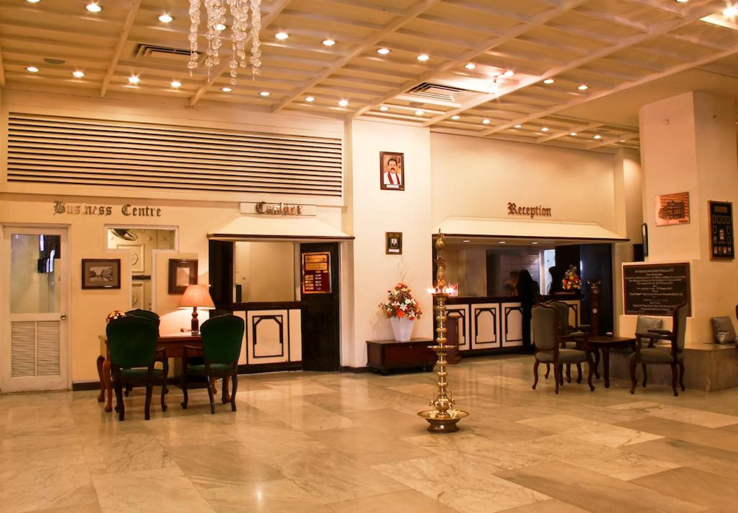 A hotel lobby with a reception desk, a business center, and a dining area with chairs and a table.