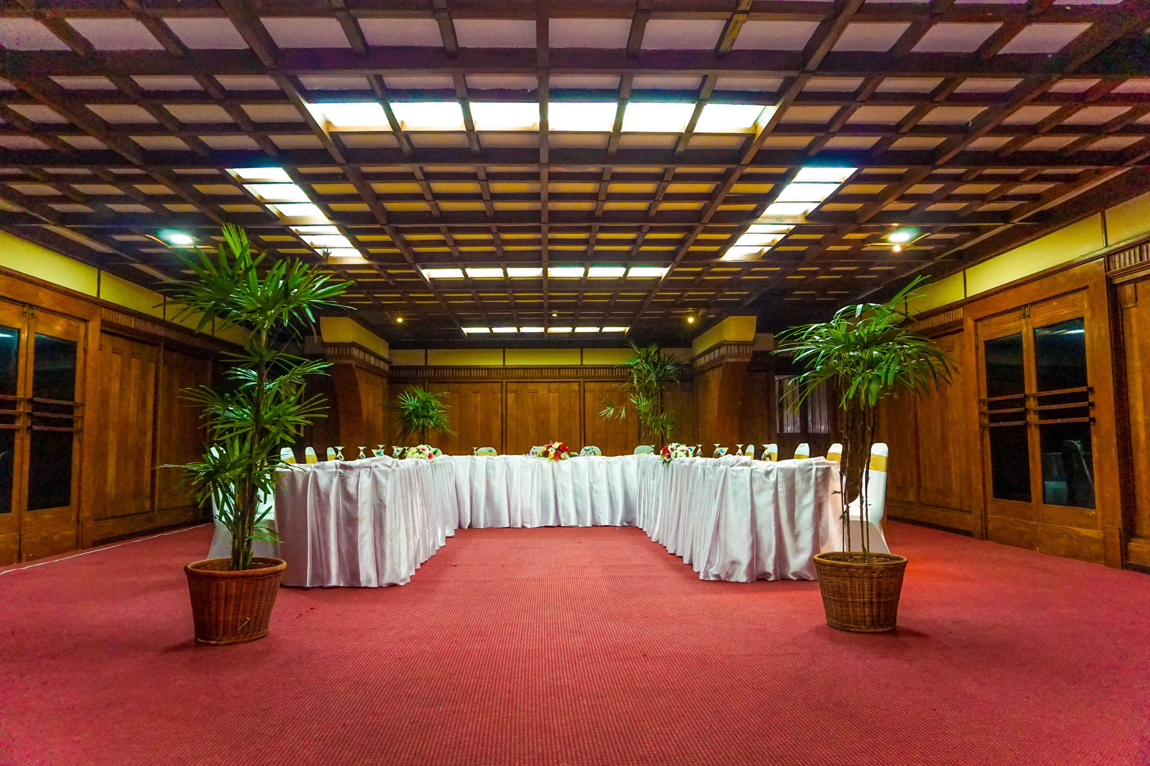 Une salle de conférence avec une longue table, une moquette rouge, des murs en bois et des luminaires au plafond.