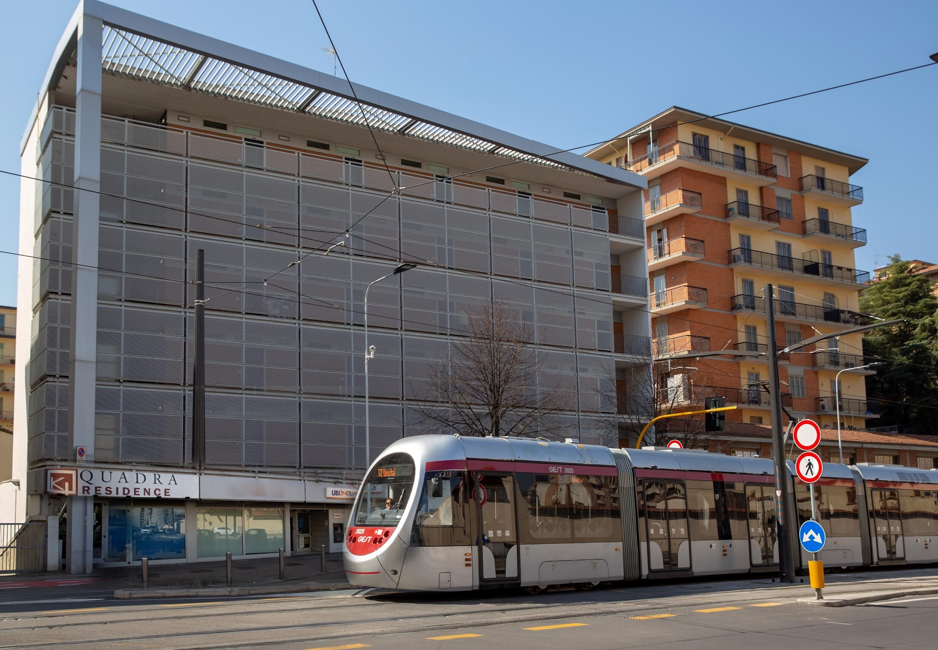 A modern building with a large glass facade and a tram passing by.