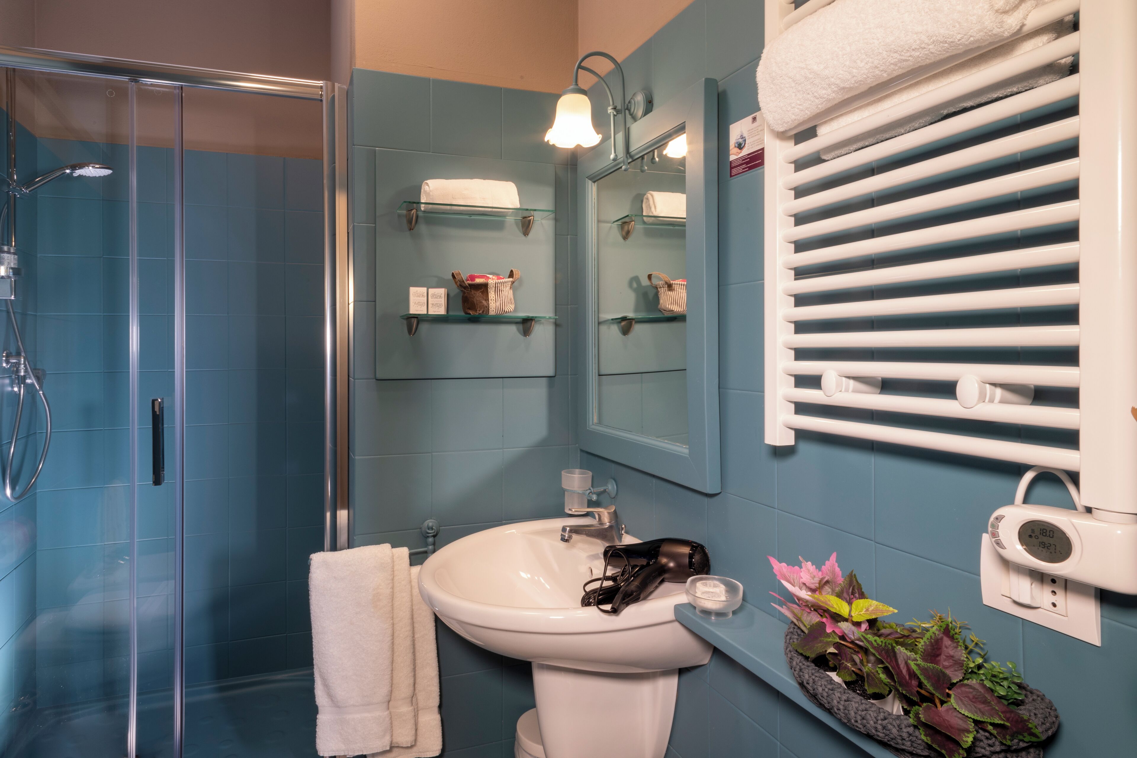 A bathroom with a glass shower enclosure, a white sink, a mirror, and a towel rack.