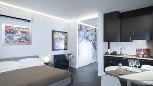 A modern hotel room with a bed, a desk with a chair, a small table with a lamp, and a large window. - Quadra Key Easy Home In Florence (Florence)