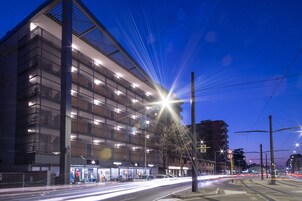 Un edificio moderno con varios pisos, grandes ventanales y una entrada a nivel de calle con tiendas.