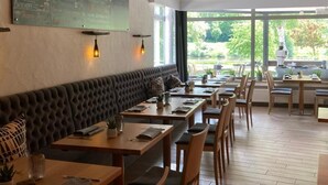 A restaurant with a chalkboard menu, wooden tables, and a cushioned bench. - Hotel Fritz (Valwig)