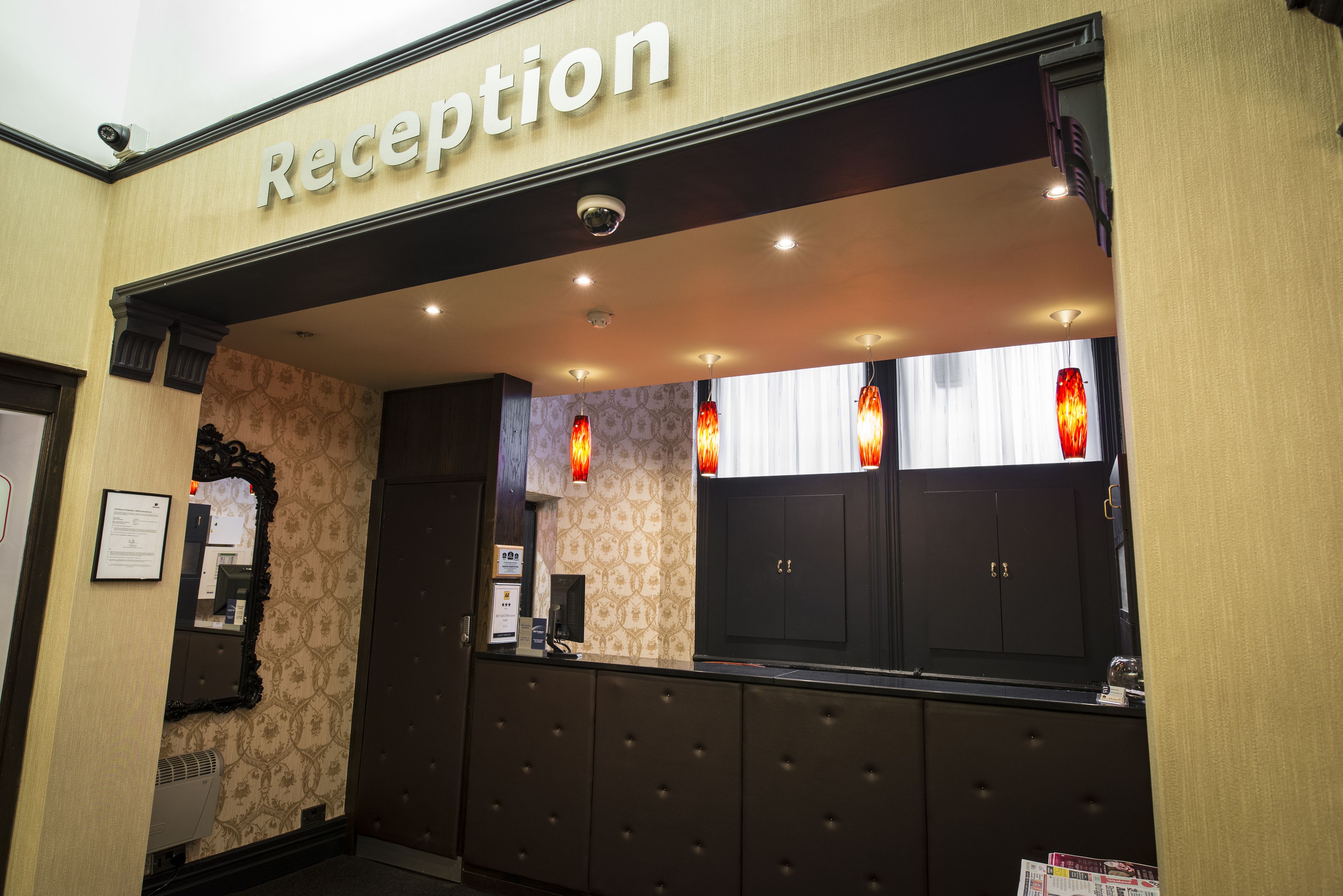 A reception area with a 'Reception' sign, a mirror, a coat rack, and a window with curtains.