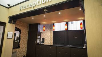 A reception area with a 'Reception' sign, a mirror, a coat rack, and a window with curtains.
