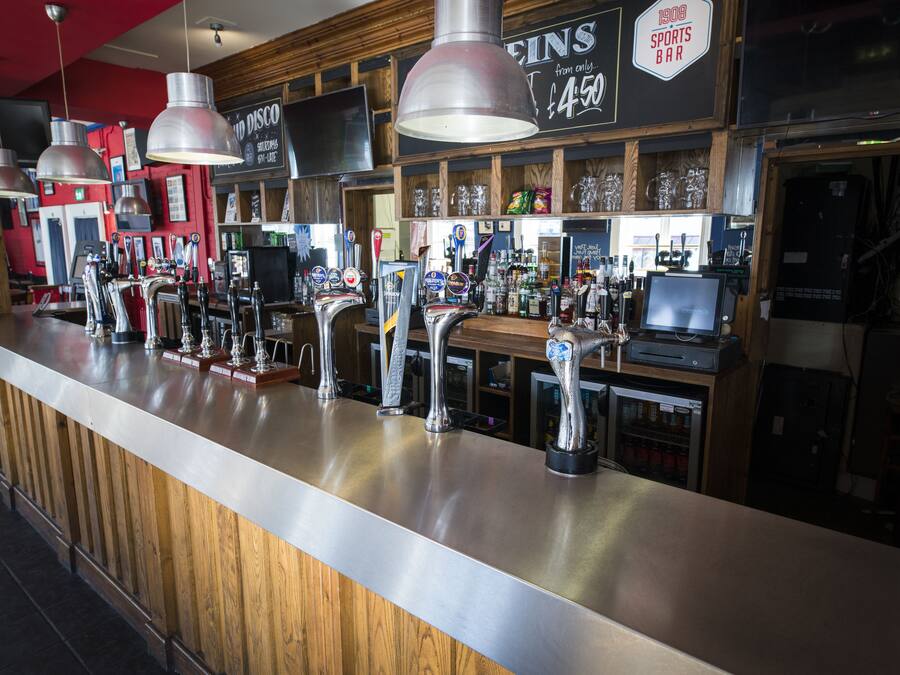 Un bar con múltiples grifos y un letrero que dice '1908 Sports Bar'.