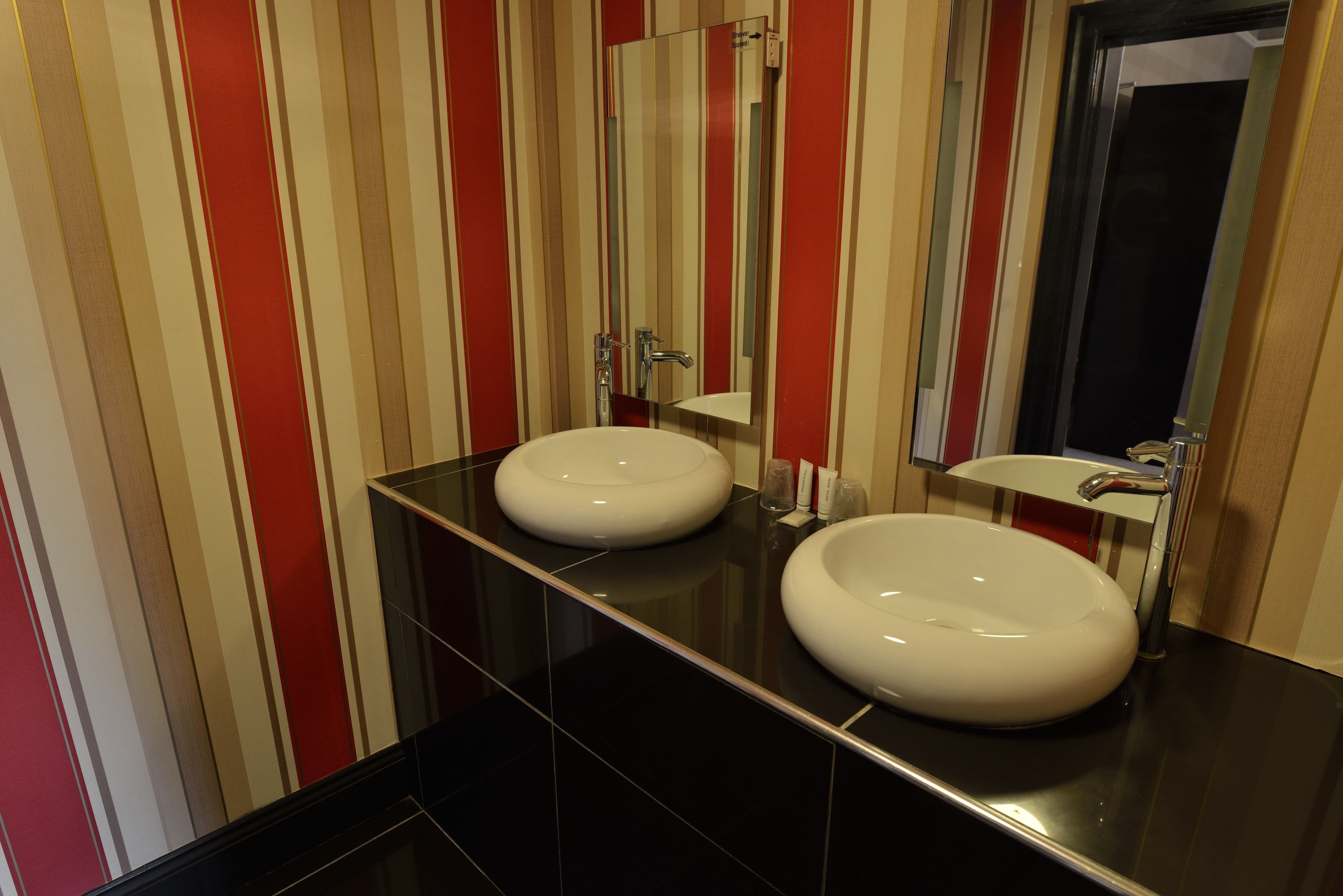 A bathroom with two sinks, a mirror, and striped walls.