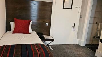 Una habitación de hotel con cama, escritorio, teléfono y puerta.