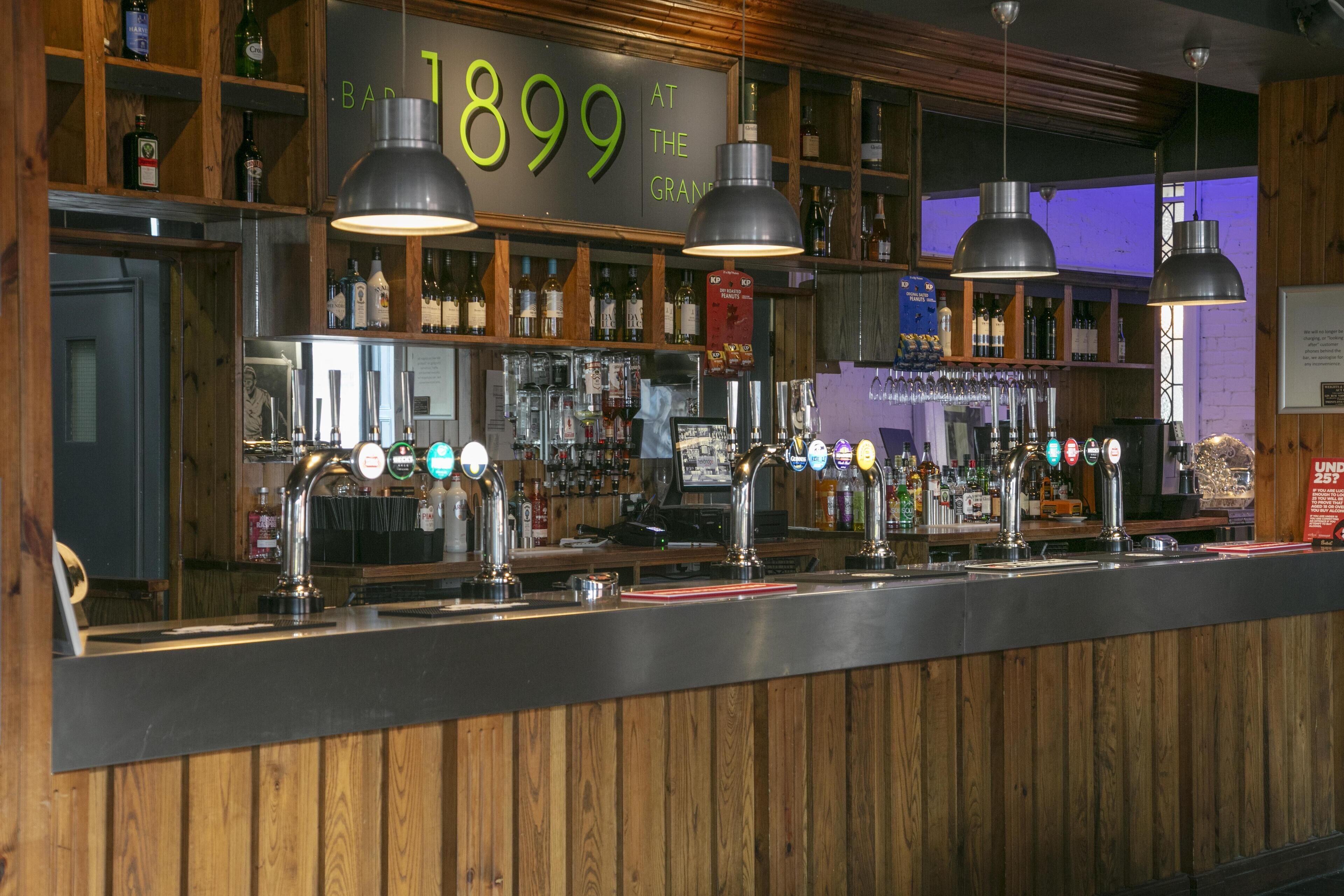Una zona de bar con paneles de madera, múltiples grifos de cerveza y estantes llenos de botellas.